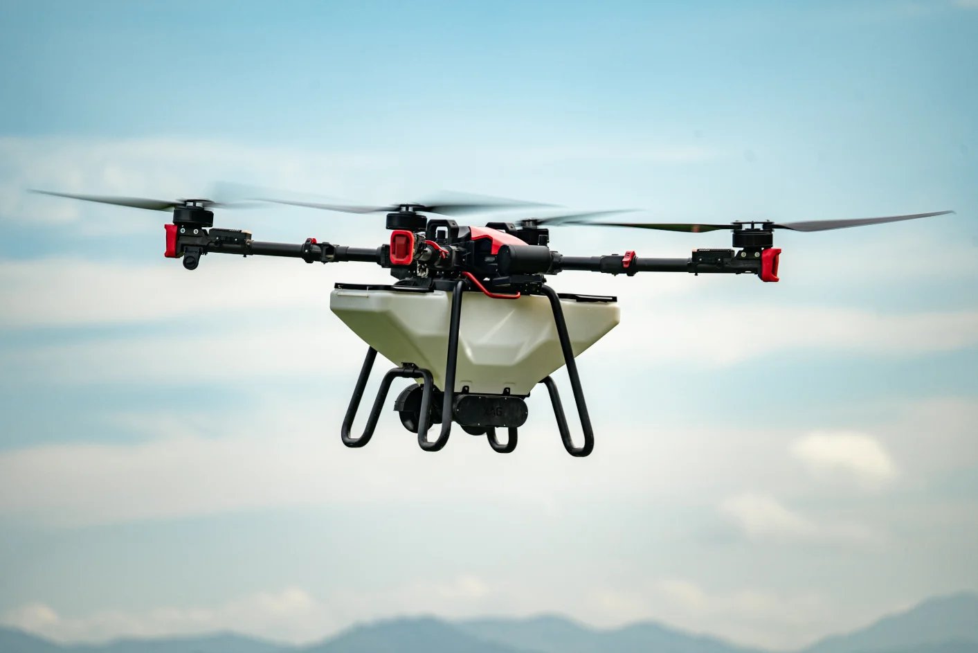Agricultural drone in flight with spray tank attachment, carrying pesticide or fertilizer for crop treatment against cloudy sky